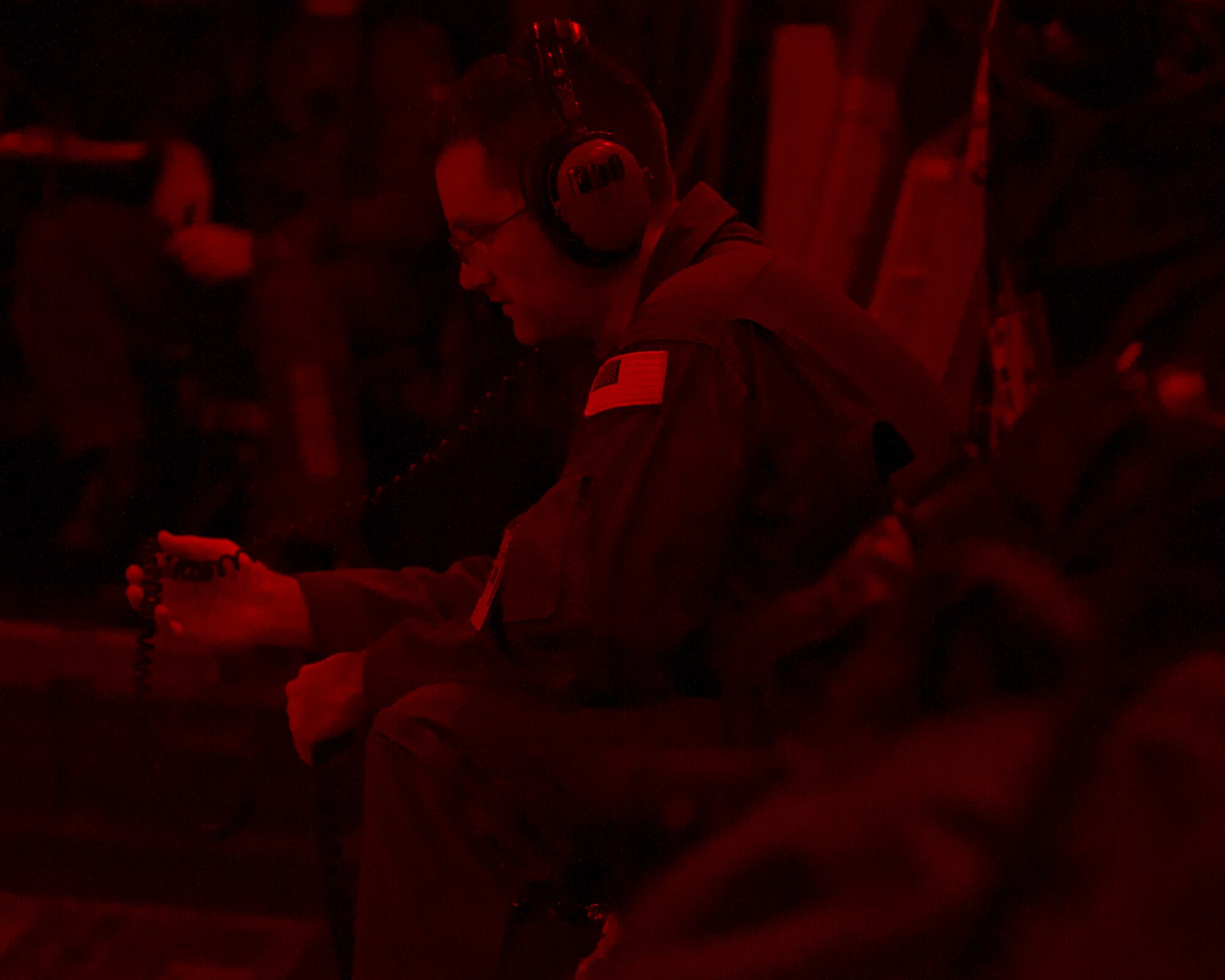 ALTUS AIR FORCE BASE, Okla. – U.S. Air Force Senior Master Sgt. Jeffrey Wilson, 58th Airlift Squadron superintendent, listens to his headset during a night training flight here, Aug. 8. Sergeant Wilson was the loadmaster instructor for two loadmaster students from the Canadian Armed Forces during the night flight. Night training is an essential part of the training mission here and prepares students for real world flying operations. (U.S. Air Force photo by Senior Airman Kenneth W. Norman / Released)