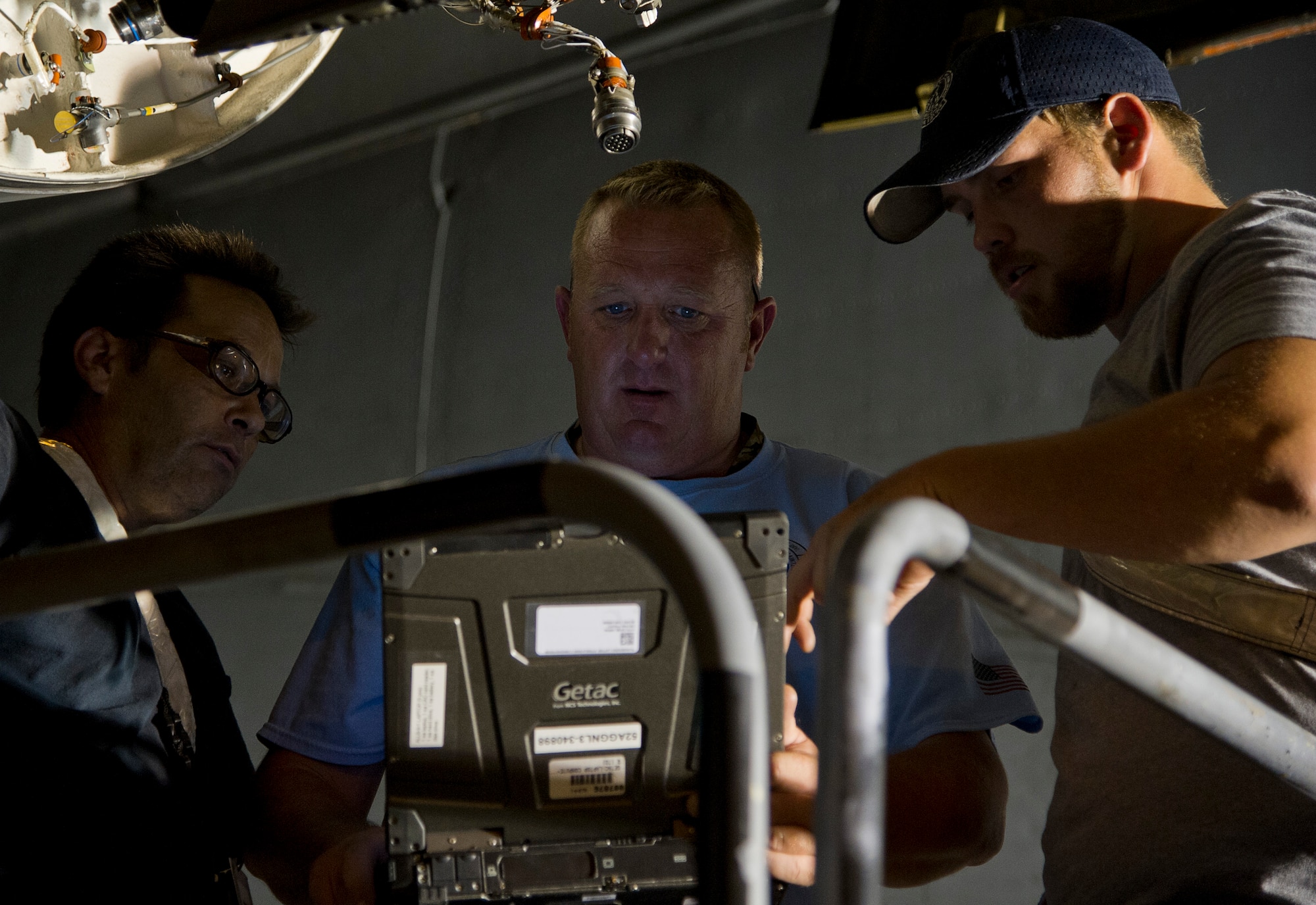ALTUS AIR FORCE BASE, Okla. – Ken Burris, 97th Maintenance Directorate electrician, Jeffrey Cunningham, 97th MX work leader, and Alex Erickson, 97th MX hydraulic technician, review a technical order on their work laptop while working on the flightline. The members of the 97th MX were replacing an Integrated Drive Generator on a U.S. Air Force C-17 Globemaster III during the night shift. The 97th MX is one of the many squadrons around base that continues to work 24 hours a day. (U.S. Air Force photo by Senior Airman Kenneth W. Norman / Released)