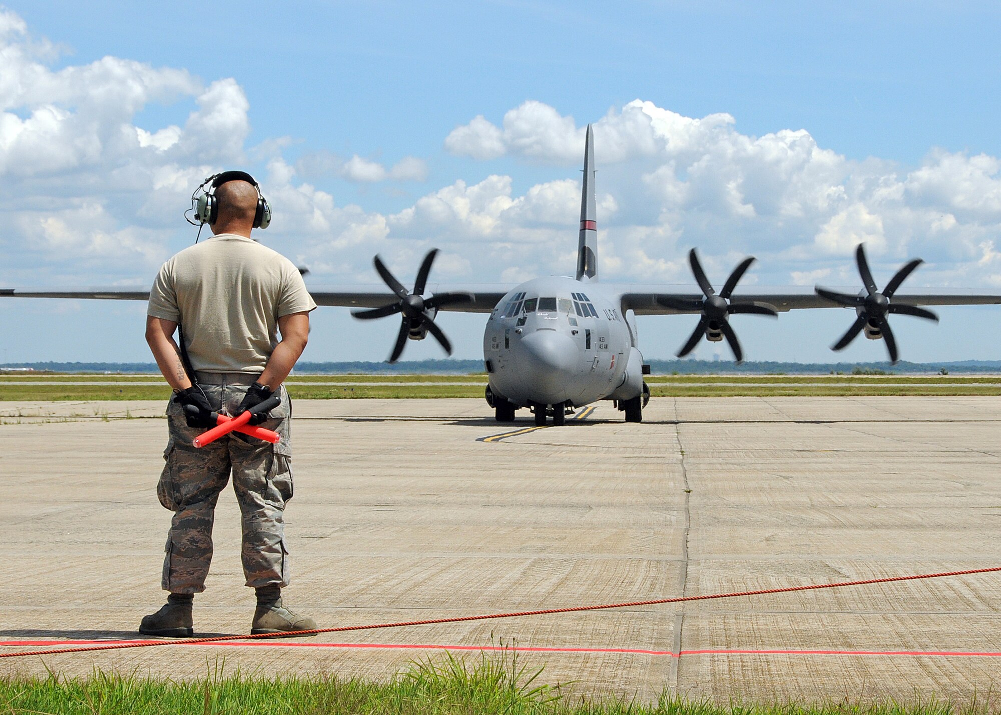 A member of the 143d Maintenance Group prepares to marshall the airplane at Quonset Air National Guard Base, North Kingstown, Rhode Island. Members of the 143rd Airborne Infantry Company and the 56th Troop Command, Rhode Island Army National Guard are aboard preparing for a combat training jump from a C-130J Super Hercules flown by members of the 143d Airlift Wing, Rhode Island Air National Guard. National Guard Photo by Master Sgt Janeen Miller (RELEASED)