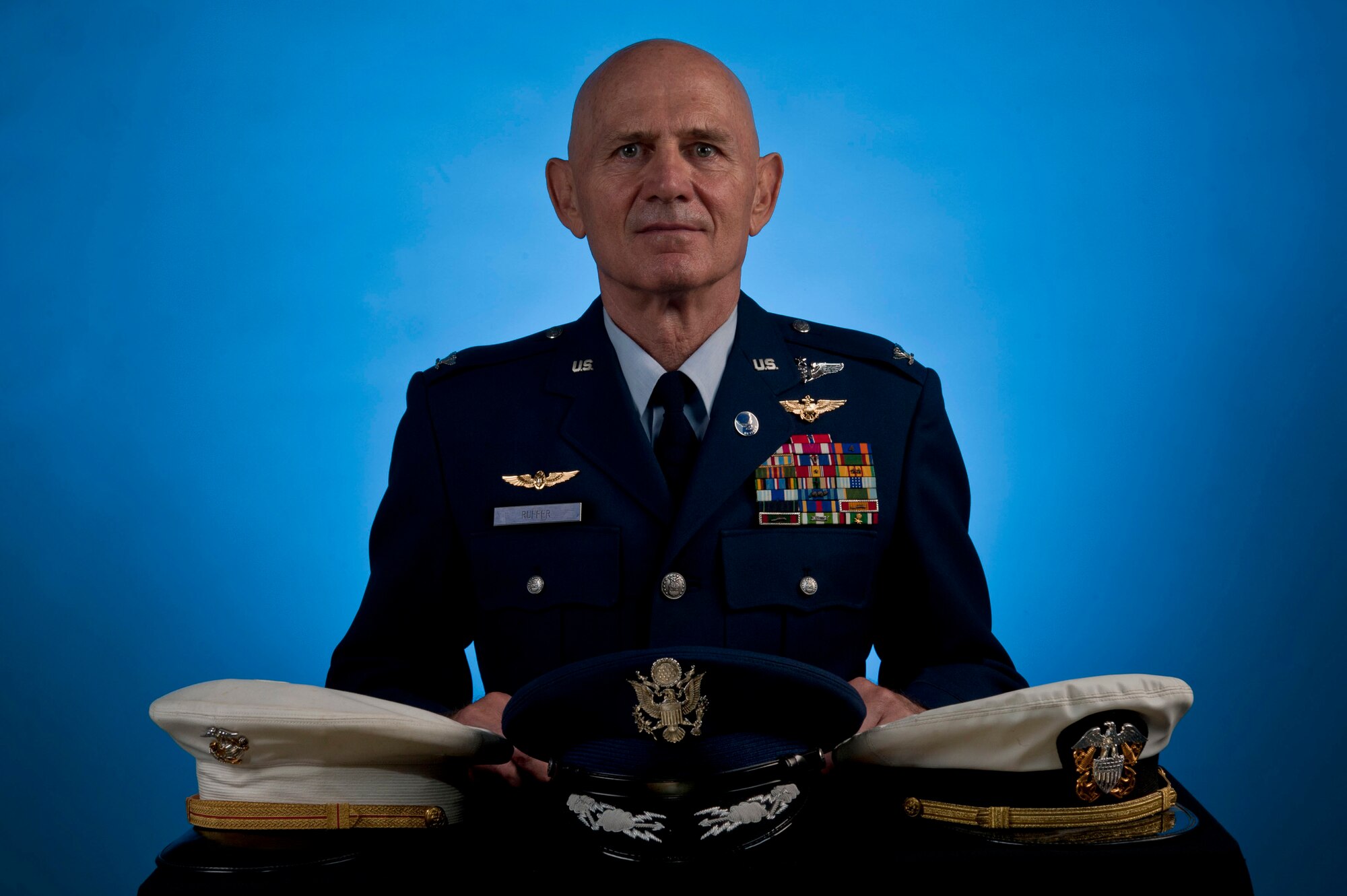 U.S. Air Force retired Col. (Dr.) James Ruffer stands behind the covers from the three different branches of the military in which he served Aug. 19, 2013, at Nellis Air Force Base, Nev. During his tours with the different branches of the military, Ruffer saw action in Vietnam, Panama and Operation Desert Storm. (U.S. Air Force photo by Senior Airman Daniel Hughes)