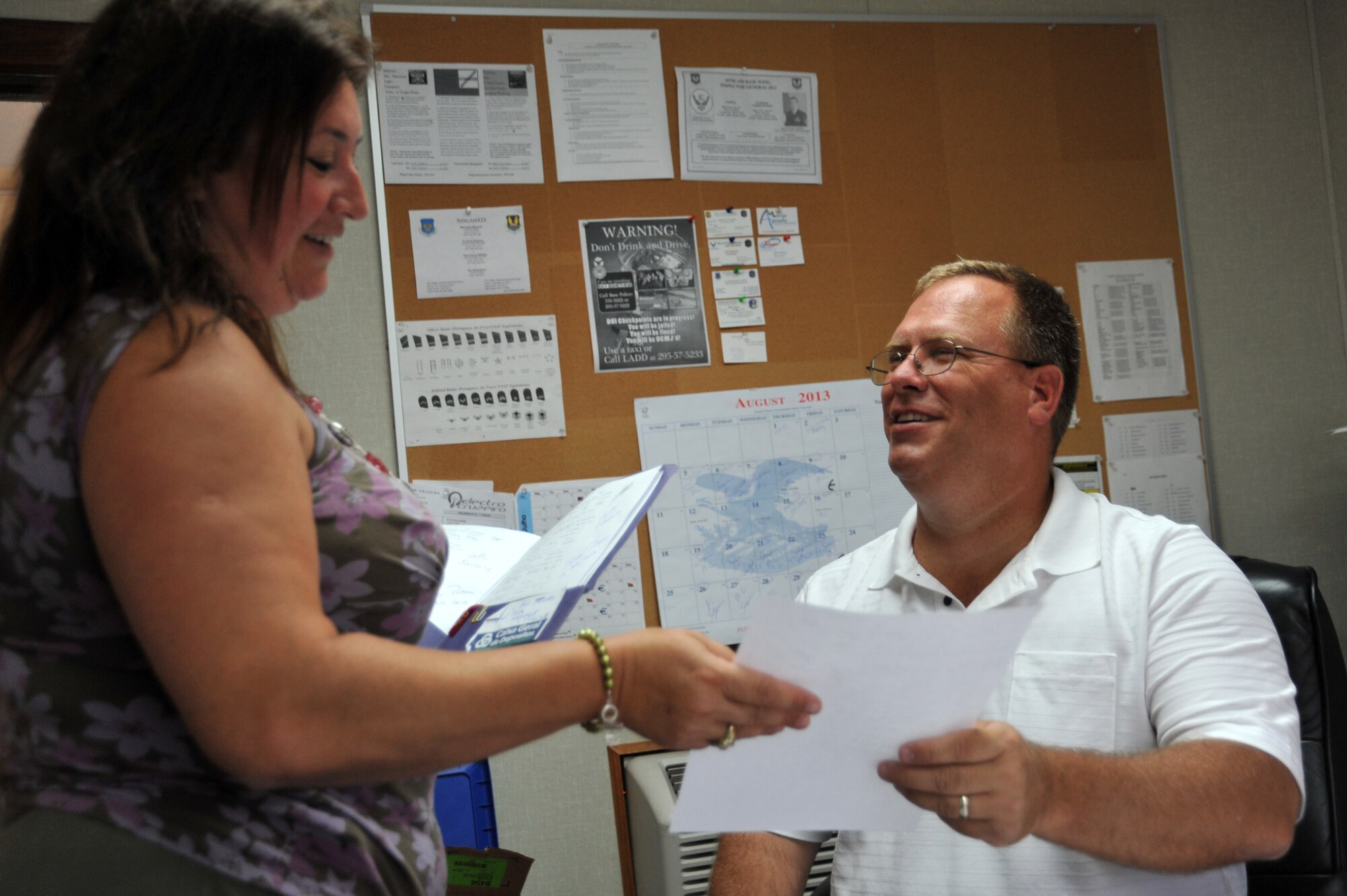 Dan Callens, 65th Civil Engineer Squadron Material Control supply technician, accepts a work order from his Portuguese coworker, Isilda Pacheco, Material Control supply technician. Callens is in charge of ensuring all materials are procured so that civil engineers can sustain Lajes Field's mission. (U.S. Air Force photo by Staff Sgt. Angelique N. Smythe)