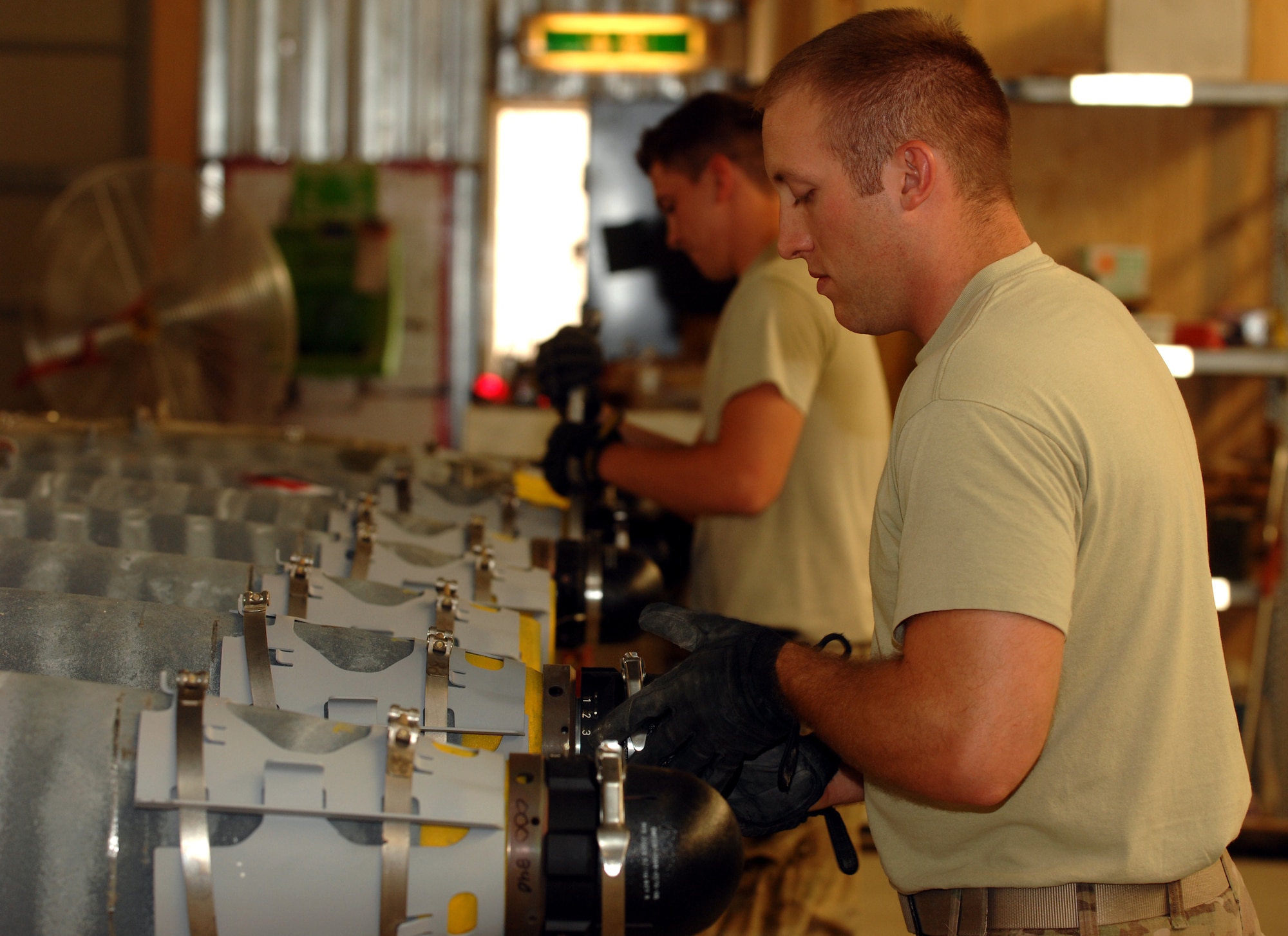 Staff Sgt. Daniel Chapman 451st Expeditionary Maintenance Squadron munitions crew chief (front), and Airman 1st Class Ty Cole, 451st EMXS munitions crew member, build Guided Bomb Unit-54 munitions for aircraft at Kandahar Airfield, Afghanistan, Aug. 16, 2013. Munitions crews work to exacting standards to ensure that weapons will function correctly and fit on the appropriate airframe. Chapman is a native of Marion, Ill., and Cole is a native of Danbury, Conn. Both Airmen are deployed from Spangdahlem Air Base, Germany. (U.S. Air Force photo/Senior Airman Jack Sanders)