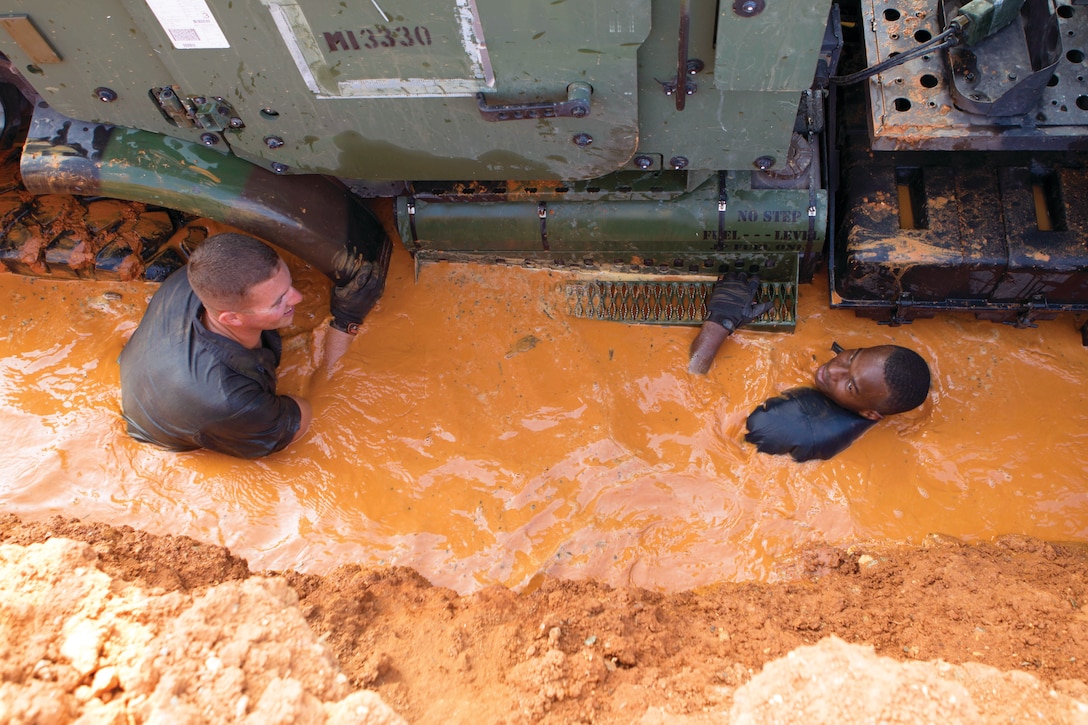 Lance Cpl. Nathan E. Craig, left, and Cpl. Oumarou A. Abdoulaye search muddy water for lost parts and tools during a military occupational specialty re-designation training course Aug. 16 at Camp Hansen. Abdoulaye is a motor transport operator with 7th Communication Battalion, III Marine Expeditionary Force Headquarters Group, III MEF, and Craig is a motor transport operator with Truck Company, Headquarters Battalion, 3rd Marine Division, III MEF.