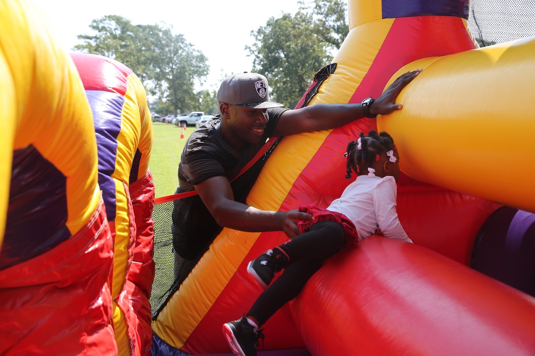 Lance Cpl. DeAngelo Rembert, a field mess Marine with Marine Wing Support Squadron 274, helps his 2-year-old daughter through an inflatable obstacle course during the squadron's family day.