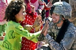 Sgt. Stephanie Tremmel, with the 86th Special Troops Battalion, 86th Infantry Brigade Combat Team, interacts with an Afghan child while visiting the village of Durrani.