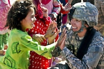 Sgt. Stephanie Tremmel, with the 86th Special Troops Battalion, 86th Infantry Brigade Combat Team, interacts with an Afghan child while visiting the village of Durrani.