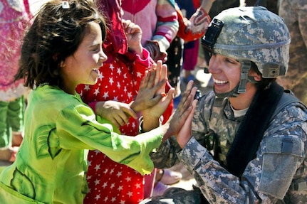 Sgt. Stephanie Tremmel, with the 86th Special Troops Battalion, 86th Infantry Brigade Combat Team, interacts with an Afghan child while visiting the village of Durrani.