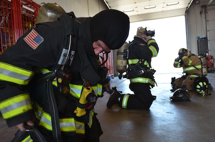 Camp Guernsey Joint Training Center Firefighter 2 Nick Long, of Cheyenne, Wyo., races to put on his protective equipment, known as bunker gear, during a timed drill at the camp's fire station, located at the Guernsey Army Airfield, near Guernsey, Wyo., July 23, 2013.