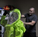 Staff Sgt. Kenneth Mize assists Army Spc. Nicole Sullivan in donning a Level-A protective suit during hazardous material training June 4, 2013, in Southwest Asia.