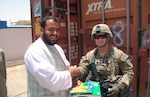 Tech. Sgt. Nathan Steele hands school supplies over to District Education Representative Bismillah Khan. The supplies were donated by Luhr Elementary School and Midway College in Kentucky.