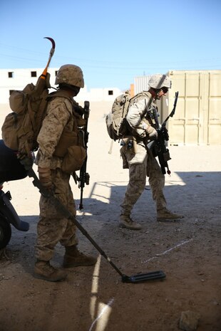 MARINE CORPS AIR GROUND COMBAT CENTER TWENTYNINE PALMS, Calif. – Private First Class Steven Flute (left), rifleman, 3rd Battalion, 7th Marine Regiment, searches for improvised explosive devices as Cpl. Colin Adams, a team leader serving with the battalion marks the potential threats while conducting a mock raid during the Integrated Training Exercise here, Aug. 12, 2013. Flute, 20, a native of Apache, Ohio, and Adams, 22, a native of Reno, Nev., located multiple simulated IEDs for their squad. The Marines assume a supporting role while deployed to Afghanistan by letting the ANA and the Afghan National Police lead in combat operations. The ITX is a training exercise held to prepare Marines prior to their upcoming deployment to Afghanistan.