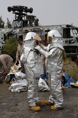 Marines with Bulk Fuel Company, 8th Engineer Support Battalion, 2nd Marine Logistics Group inspect one another’s proximity suit prior to engaging in a live fire exercise aboard Marine Corps Air Station Cherry Point, Aug. 28, 2013. When worn correctly the suits will protect the wearer from high temperatures, making them essential for firefighters. (U.S. Marine Corps photo by Lance Cpl. Shawn Valosin)