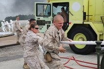 Marines with Bulk Fuel Company, 8th Engineer Support Battalion, 2nd Marine Logistics Group pull fire hoses as fast as they can so Marines fighting a fire can move more freely and effectively to extinguish the blaze during a live fire training exercise aboard Marine Corps Air Station Cherry Point, Aug. 28, 2013. The exercise was part of Bulk Fuel Company’s annual training requirement. (U.S. Marine Corps photo by Lance Cpl. Shawn Valosin)