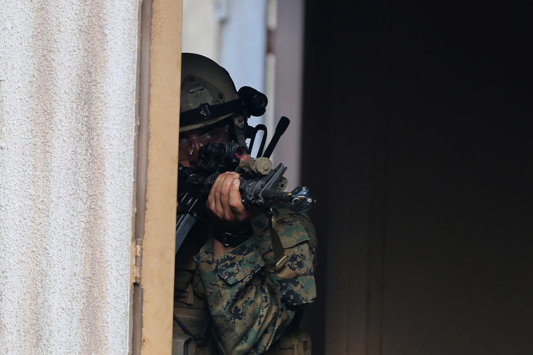 A Marine serving with Alpha Company, 1st Reconnaissance Battalion, responds to simulated small-arms fire during a mission rehearsal exercise here, Aug. 20, 2013. During the exercise, Marines performed a night raid on a military operations in urban terrain town and detained possible enemy combatants. The MRX assessed the Marines' ability to execute their mission and coordinate logistics with their command element as they prepare to deploy with the 11th Marine Expeditionary Unit next year.