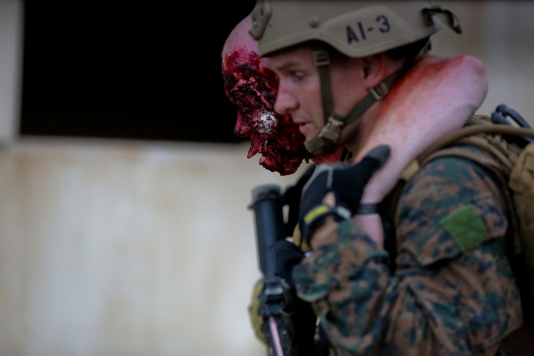 A Marine serving with 1st Reconnaissance Battalion helps a simulated hostage to safety after clearing the house he was held in of enemy combatants during a mission rehearsal exercise here, Aug. 20, 2013. Marines responded to simulated small-arms fire and artillery rounds with suppressing fire and patrols through the area. An evaluator followed each squad of Marines and assessed their various skills including tactics, coordination and execution during the mission.