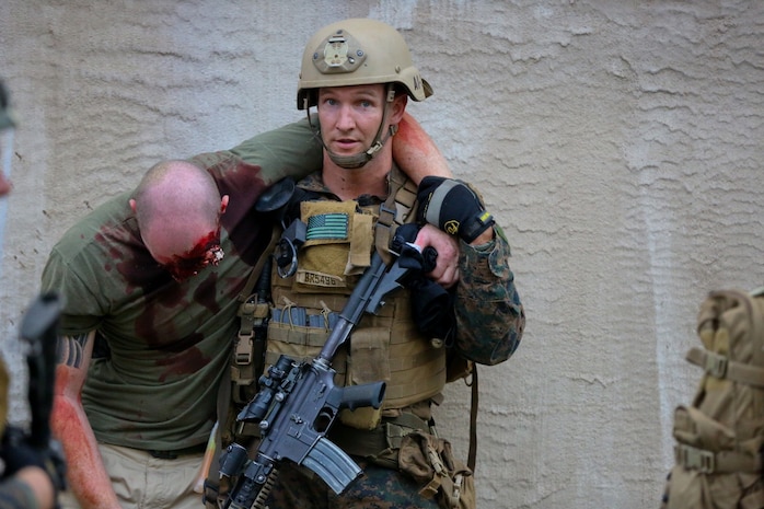 A Marine serving with 1st Reconnaissance Battalion helps a simulated hostage to safety after clearing the house he was held in by enemy combatants during a mission rehearsal exercise here, Aug. 20, 2013. Marines responded to simulated small-arms fire and artillery rounds with suppressing fire and patrols through the area. An evaluator followed each squad of Marines and assessed their various skills including tactics, coordination and execution during the mission.