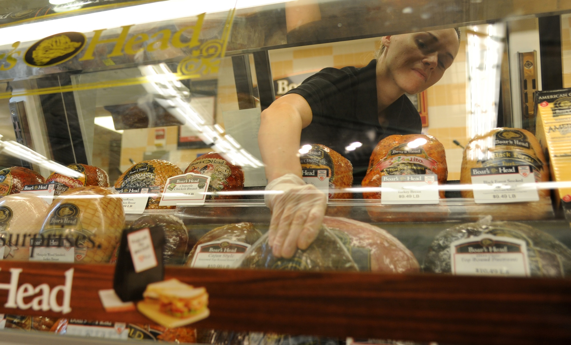 Brooke Michael, Defense Commissary Agency deli clerk, places sandwich meat in a  display caseat the commissary Aug. 29, 2013, Keesler Air Force Base, Miss.  The commissary restored its Monday hours after previously being closed on Mondays due to civilian furloughs.  (U.S. Air Force photo by Kemberly Groue)