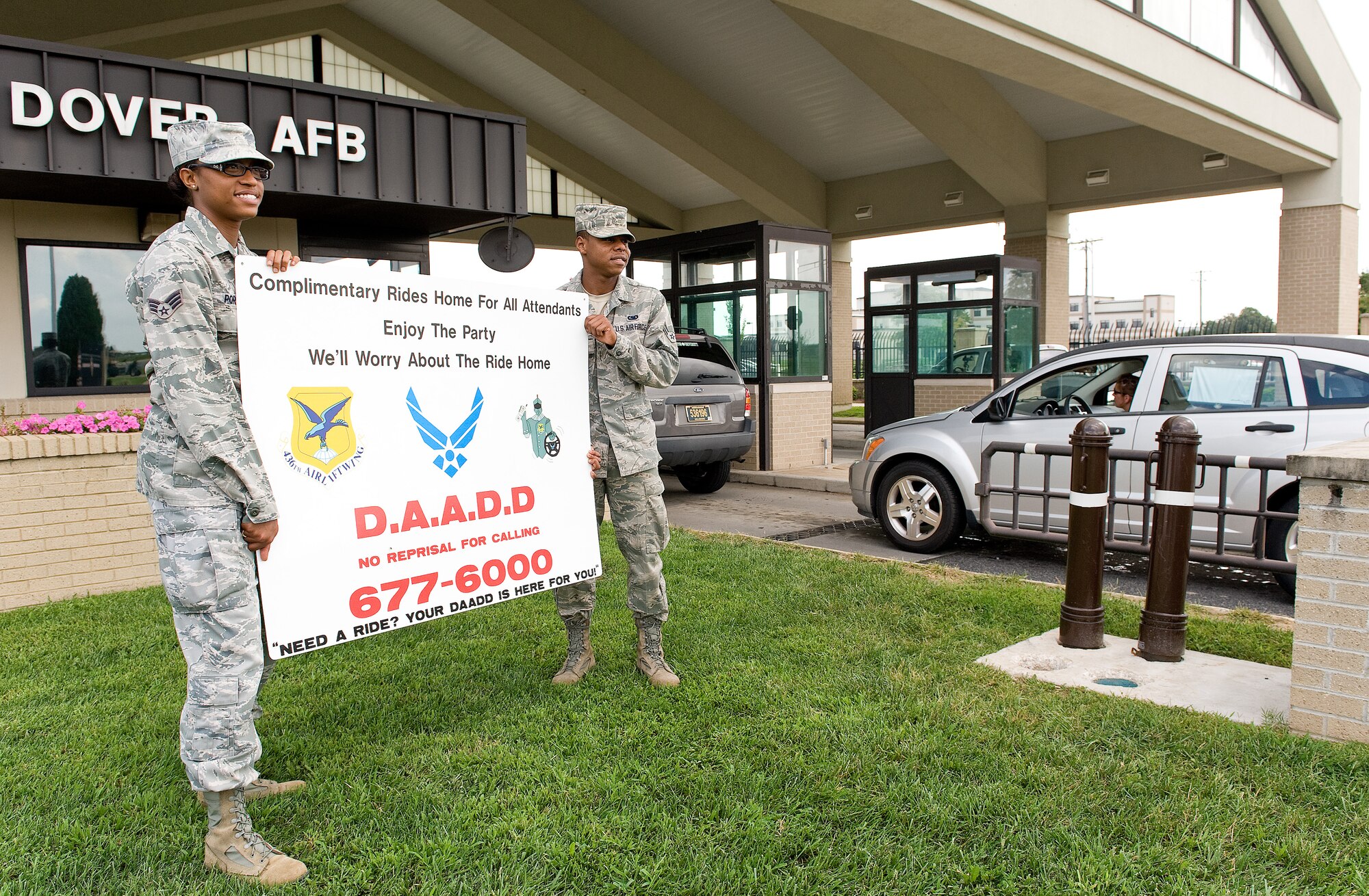 Senior Airman Letiesha Porter, left, with the 436th Comptroller Squadron, and Airman 1st Class Travis Cabb, 436th Logistics Readiness Squadron, hold the Dover Airmen Against Drunk Driving information sign at the main gate August 29, 2013, at Dover Air Force Base, Del. Porter and Cabb, members of D.A.A.D.D., reminded personnel to be safe Labor Day weekend. (U.S. Air Force photo/Roland Balik)
