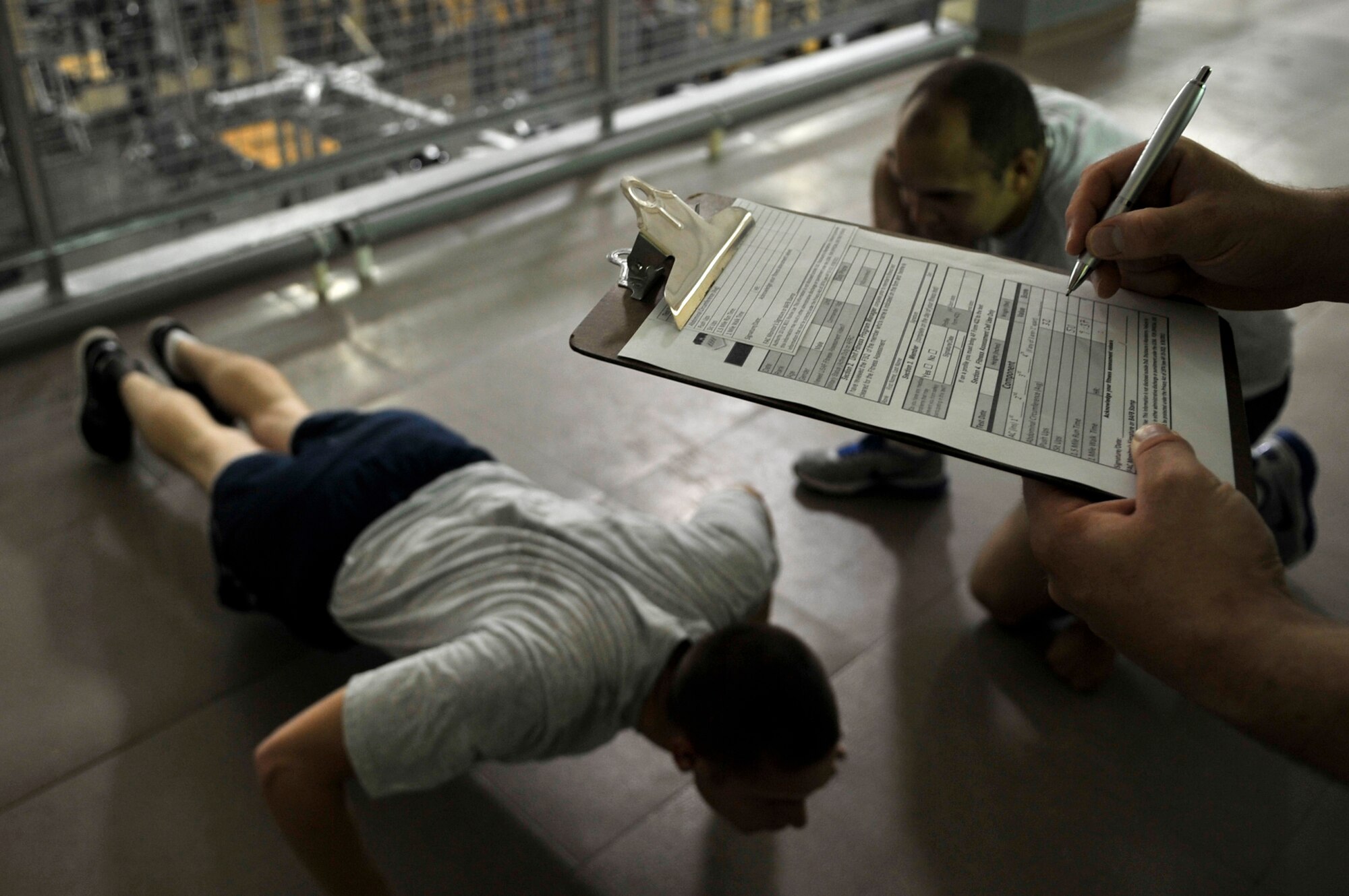 Senior Airman Jonathon Crouch, 2nd FSS Services journeyman must show integrity when grading Senior Airman James Hart's fitness assessment on Barksdale Air Force Base, August 27, 2013. Senior Airman Christopher Santos, 2nd CES electrical systems journeyman also keeps count of Hart's push-ups to maintain accountability, which is one aspect of integrity. (U.S. Air Force photo illustration/Airman 1st Class Benjamin Raughton)