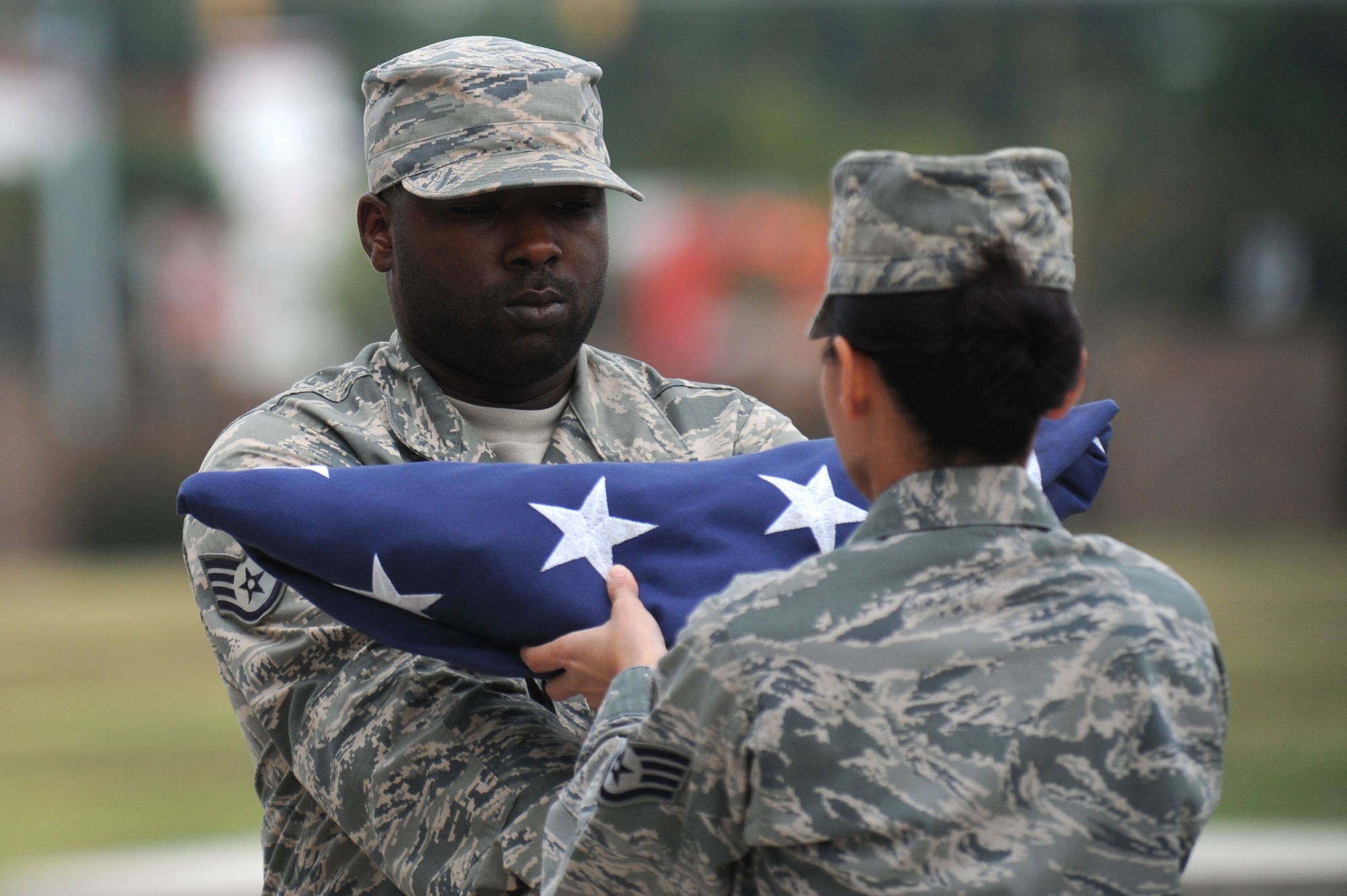 Staff Sgt. Jai Holt hands the flag to Staff Sgt. Thomas White, members of the flag detail Airmen, during the final Air Force District of Washington retreat ceremony of the year at Joint Base Andrews, Md., Aug. 29, 2013. Holt is the AFDW commander’s enlisted aide. White is the AFDW unit training manager. (U.S. Air Force photo by Tech. Sgt. Tammie Moore)