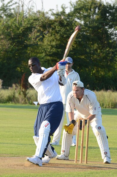 UPWOOD, United Kingdom – Tech. Sgt. Quami King, 423rd Medical Squadron, swings for the ball a Huntingdonshire District Council cricket team member bowled during the first game played by the team Aug. 28 at Upwood Cricket Club, Upwood, United Kingdom. Behind each batsman is a target called a wicket. One designated member of the fielding team, the bowler, is given a ball and attempts to bowl the ball from one end of the pitch to the wicket behind the batsman on the other side of the pitch. The batsman tries to prevent the ball from hitting the wicket by striking the ball with a bat. If the bowler succeeds in hitting the wicket, or if the ball, after being struck by the batsman, is caught by the fielding team before it touches the ground, the batsman is dismissed.  (U.S. Air Force photo by Tech. Sgt. Chrissy Best)