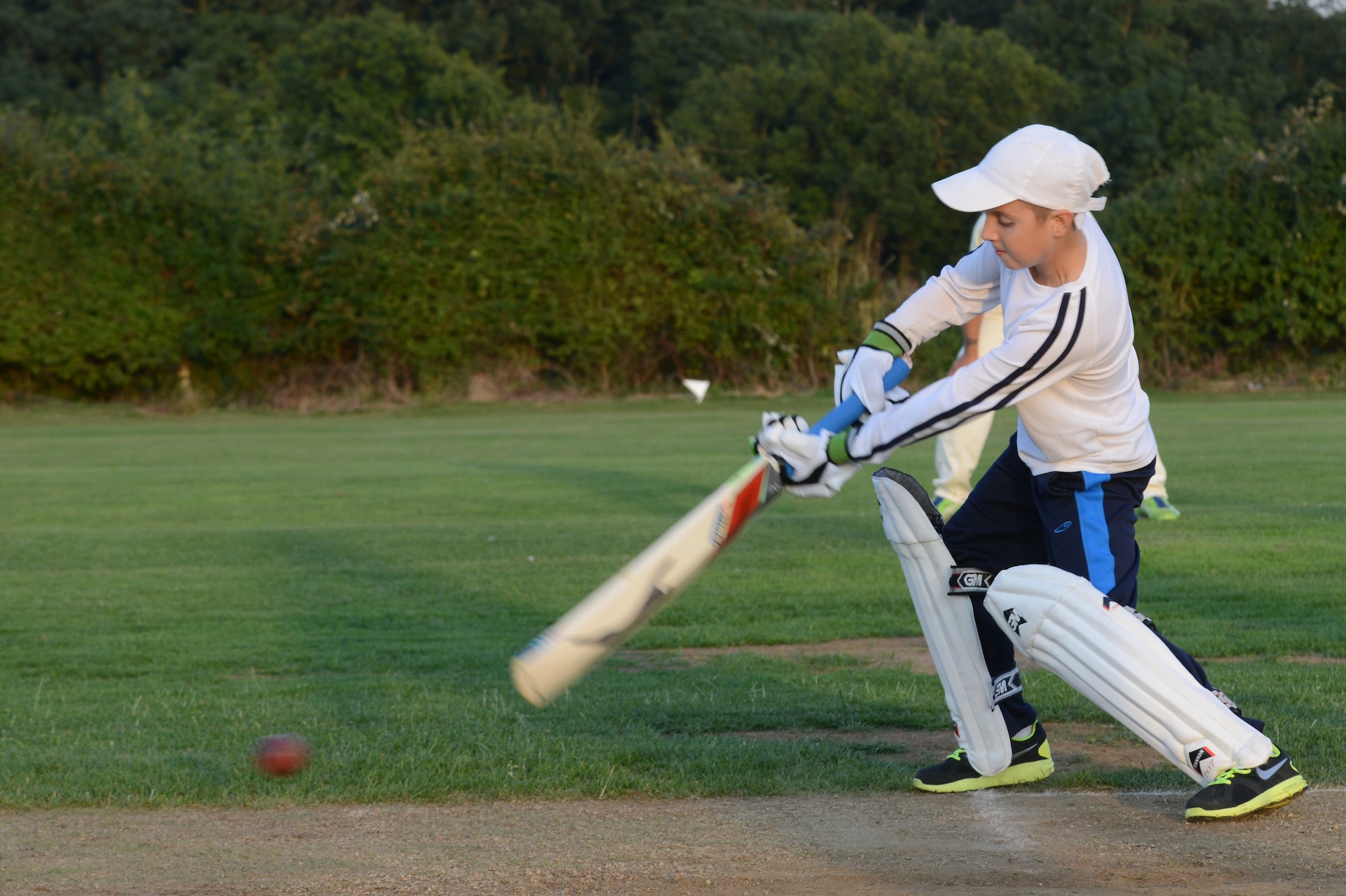 UPWOOD, United Kingdom – Grant Sweeney, son of Col. Steven Sweeney, 423rd Air Base Group commander, swings for the ball a Huntingdonshire District Council cricket team member bowled during the first game played by the team Aug. 28 at Upwood Cricket Club, Upwood, United Kingdom. Behind each batsman is a target called a wicket. One designated member of the fielding team, the bowler, is given a ball and attempts to bowl the ball from one end of the pitch to the wicket behind the batsman on the other side of the pitch. The batsman tries to prevent the ball from hitting the wicket by striking the ball with a bat. If the bowler succeeds in hitting the wicket, or if the ball, after being struck by the batsman, is caught by the fielding team before it touches the ground, the batsman is dismissed.  (U.S. Air Force photo by Tech. Sgt. Chrissy Best)