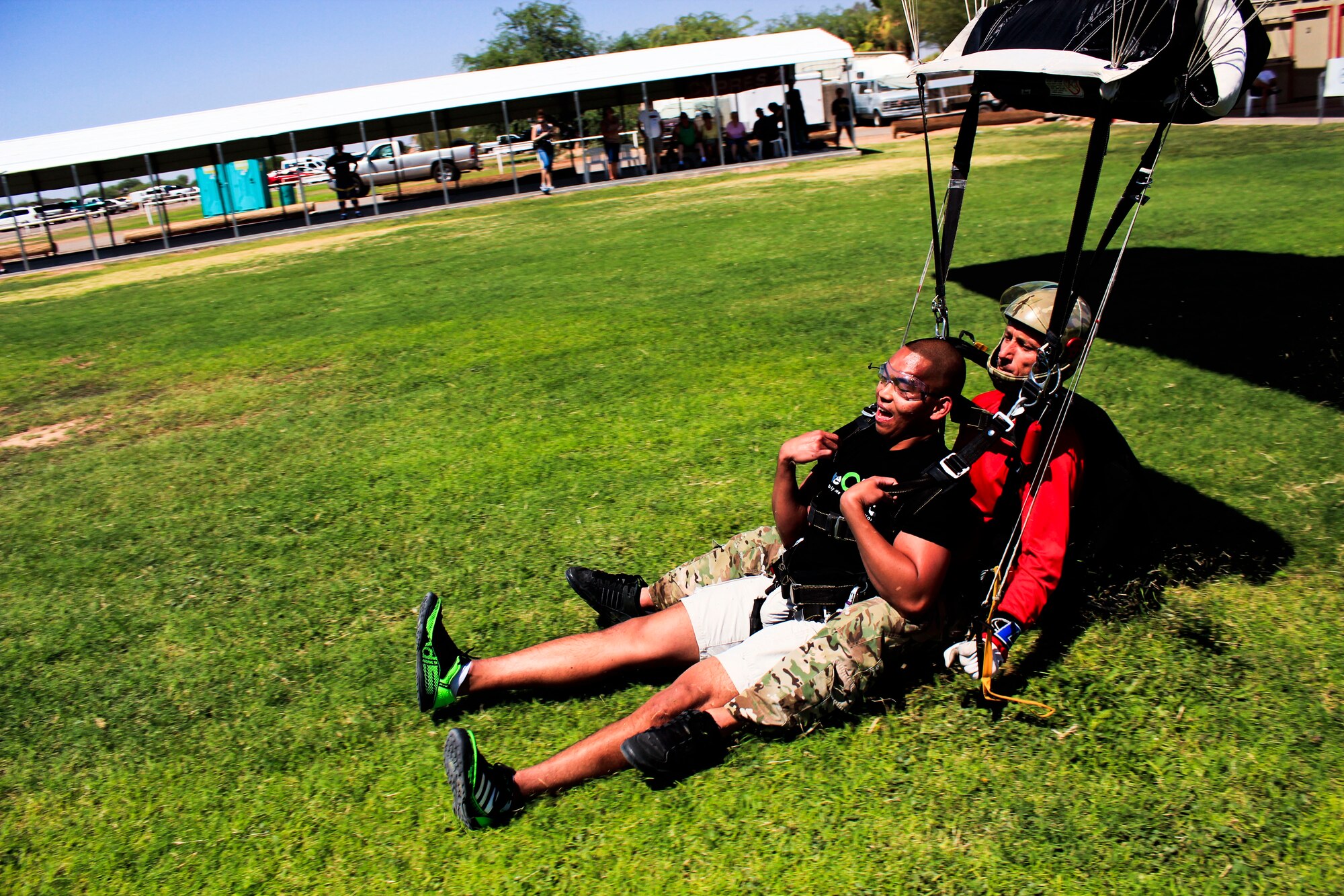 Airman 1st Class Brando Sompie, 56th FSS, and a skydiving instructor slide onto the ground as they land. (Courtesy photo)