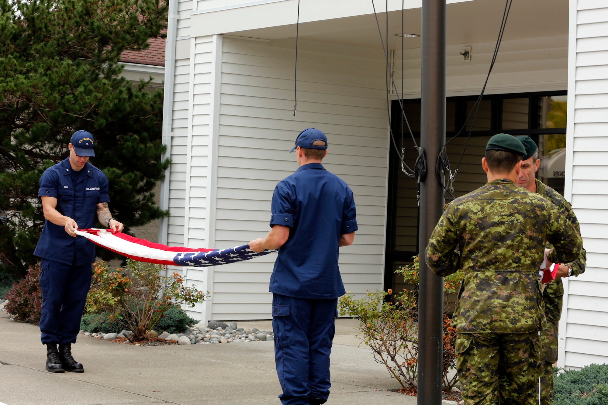 U.S. Coast Guard and Canadian military personnel fold the United States and Canadian flags during the closing ceremony of this year’s Josh Fueston Memorial Swim to Live, Aug. 25, 2013, in Bellingham, Wash. The flags were presented to families who lost loved ones to post-traumatic stress disorder. (U.S. Air Force photo/Capt. Rachel Ianacone)