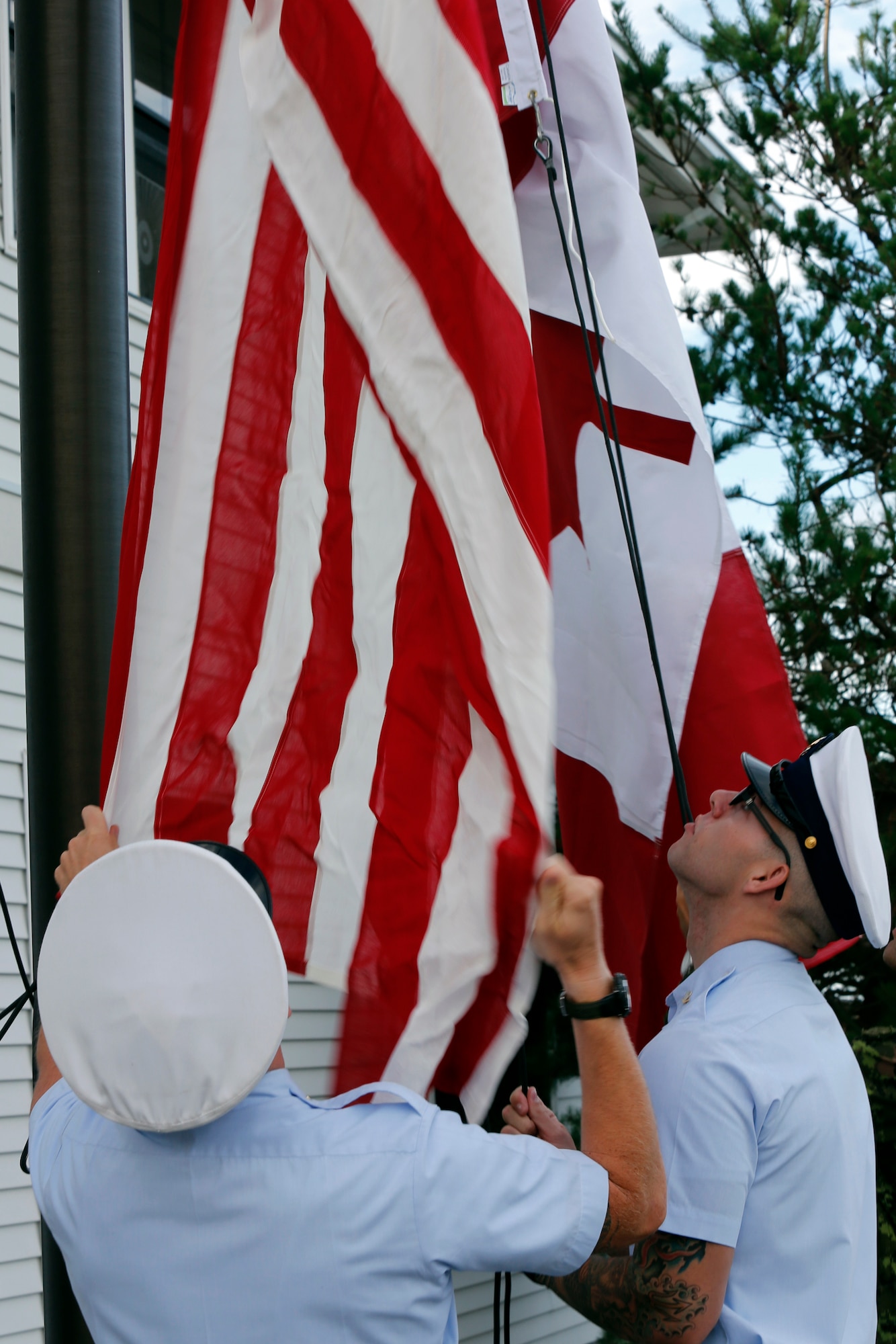 U.S. Coast Guard personnel lower the United States and Canadian flags to half-staff during the opening ceremony of the 2013 Josh Fueston Memorial Swim to Live, Aug. 25, 2013, in Bellingham, Wash. The flags were lowered to pay honor to U.S. and Canadian military members who have lost their battles with post-traumatic stress disorder. (U.S. Air Force photo/Capt. Rachel Ianacone)
