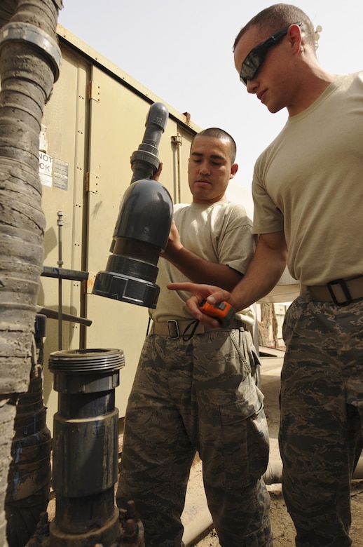 Senior Airmen Dennis Weaver and Norman Anderson, 380th Expeditionary Civil Engineer Squadron heating, ventilation and air conditioning journeymen, try to re-fit new pipes at an undisclosed location in Southwest Asia, Aug. 7, 2013. The pipes they are trying to re-fit belong to an air conditioning system for a U-2 Dragon Lady hangar here. Weaver calls Sacramento, Calif., home and is deployed from Luke Air Force Base, Ariz. Anderson calls East Hartford, Conn., home and is deployed from Joint Base McGuire-Dix-Lakehurst, N.J. (U.S. Air Force photo by Staff Sgt. Jacob Morgan/Released)