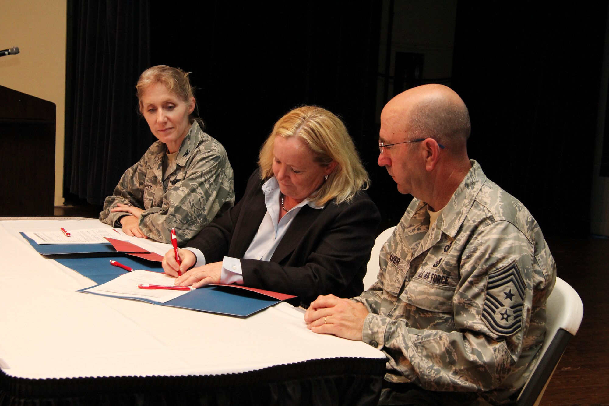 Sharon Shores, Corvias Military Living program manager, assists U.S. Air Force Col. Jeannie Leavitt, 4th Fighter Wing commander, and Chief Master Sgt. Jeffrey Craver, 4th FW command chief, with signing their base housing leases during a town hall meeting at Seymour Johnson Air Force Base, N.C., Aug. 13, 2013.  Corvias Military Living will privatize Seymour Johnson Air Force Base housing beginning Sept. 1. (Courtesy photo)