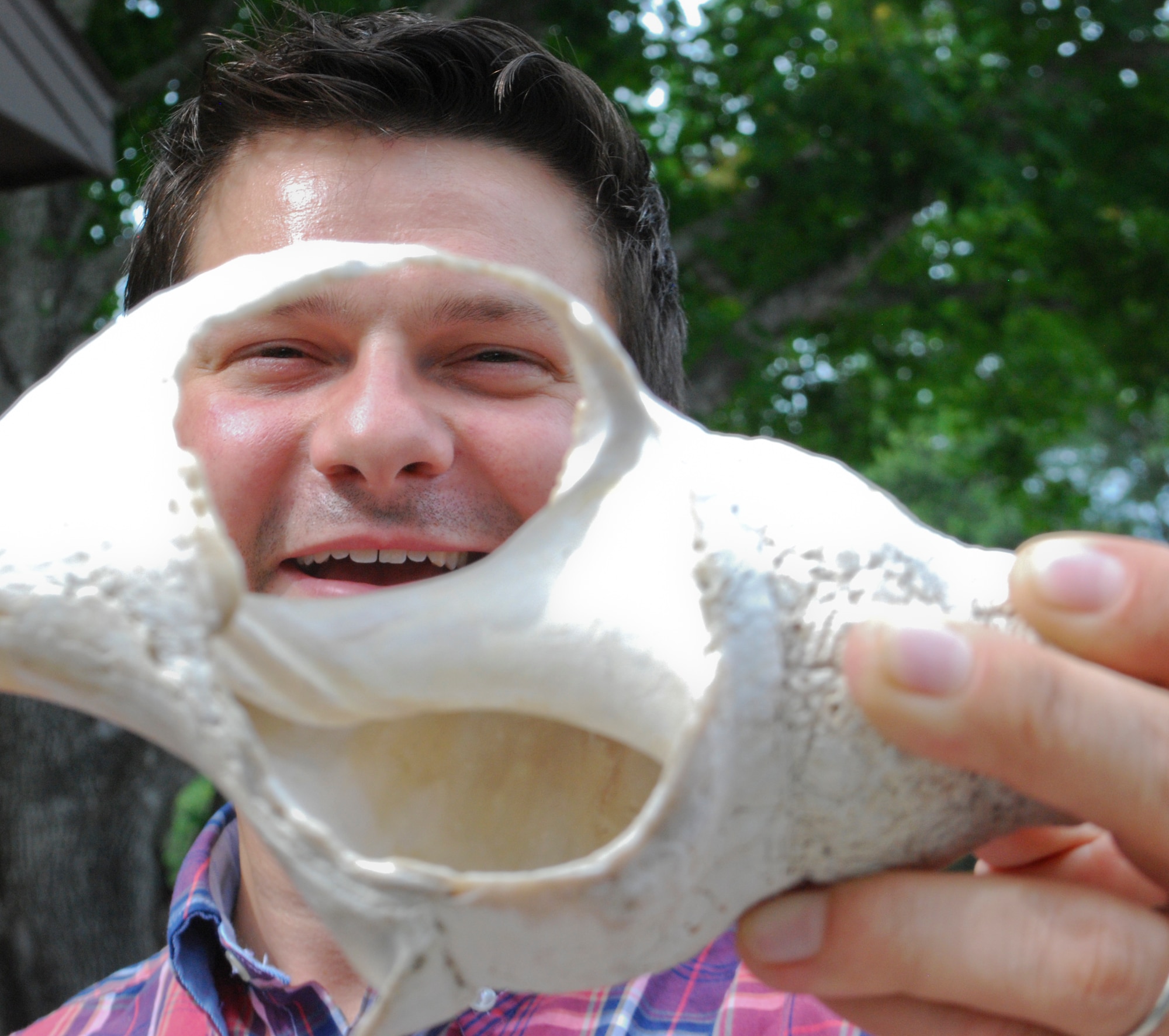 Mr. Craig Dengel, a Louisiana State University doctorate of archaeology student, peers through a conch shell Aug. 26 at the 325th Civil Engineer Squadron Natural Resources building. Shells like this may have been used as tools 1,500 years ago. (U.S. Air Force photo by 2nd Lt. Christopher Bowyer-Meeder) 