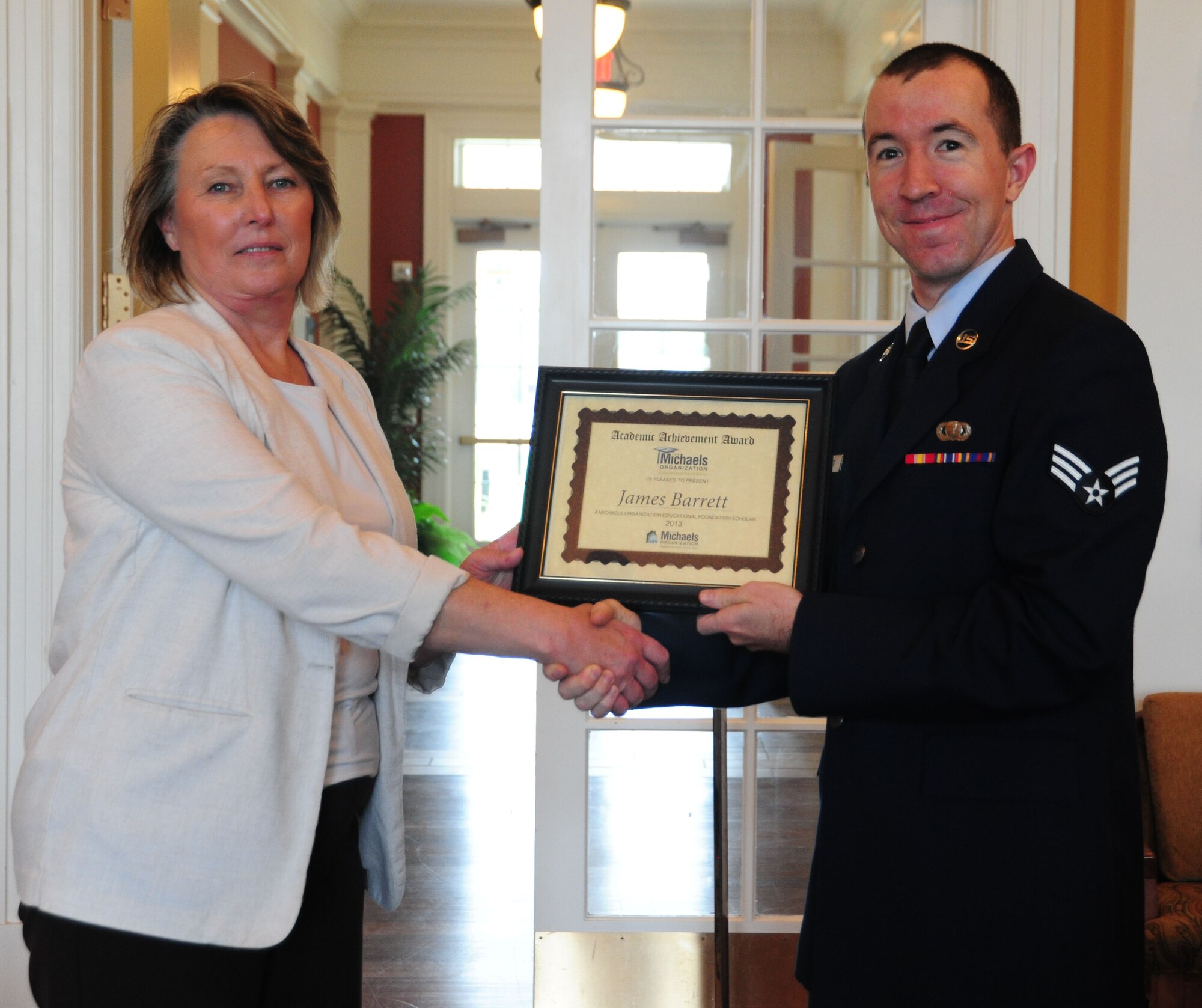 Mary Jette, Liberty Park at Andrews community manager, presented Senior Airman James Barrett, 11th Contracting Squadron contract specialist, with a $2,000 scholarship, Aug. 28, 2013, during a luncheon held in his honor at the Joint Base Andrews, Md., Liberty Park welcome center. The Michaels Organizational Educational Foundation scholarship at Liberty Park seeks to enhance residents of its housing community’s educational opportunities. (U.S. Air Force photo/ Ms. Amber J. Russell)