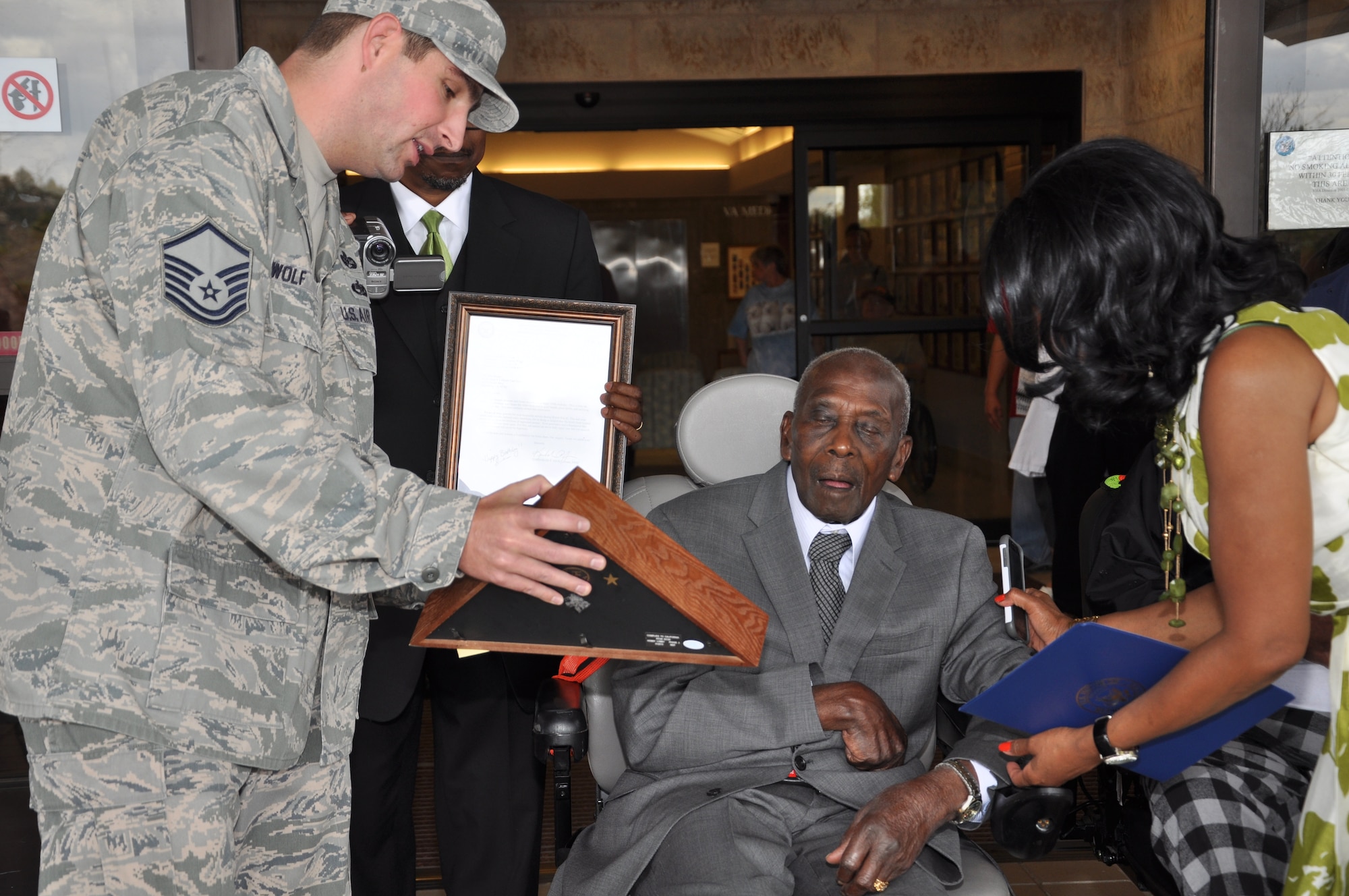 BIG SPRING, Texas- Master Sgt. Jacob Wolf, 17th Legal Office superintendent,  presents Otho Henry, World War II Army veteran, with a flag for his 100th birthday at the West Texas Veterans’ Affairs Health Care System Facility Aug. 23. Henry was stationed in Wyoming, England and France during the war. (U.S. Air Force photo/ Airman 1st Class Erica Rodriguez)