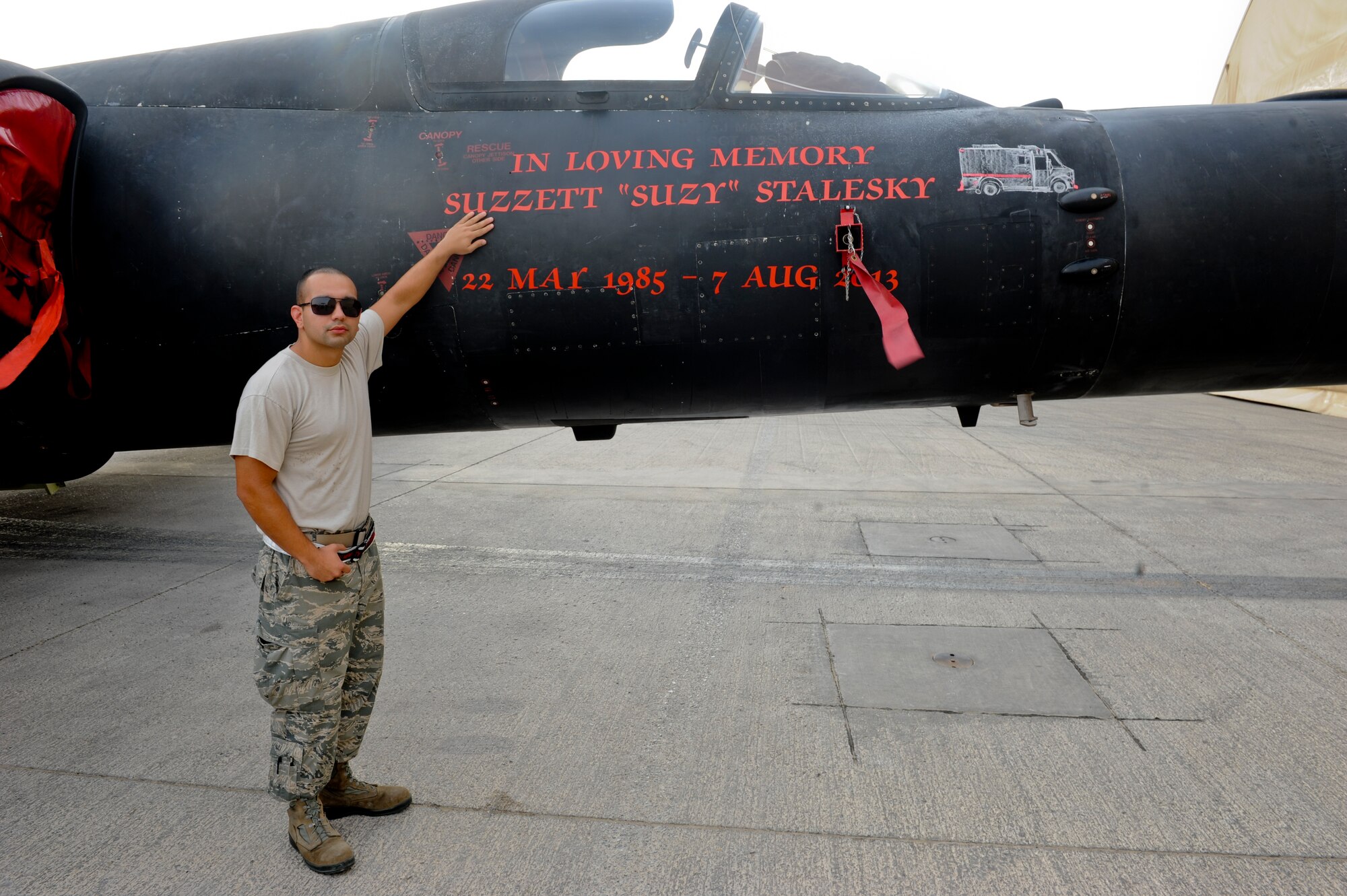 U.S. Air Force Senior Alejandro Ruiz, 99th Expeditionary Reconnaissance Squadron, physiological support division technician, stands next to a memorial dedication to U.S. Air Force Staff Sgt. Suzzett Stalesky, a member of the U-2 family who recently passed away from cancer. Ruiz was close friends with Stalesky and has known her for more than 6 years. (U.S. Air Force photo by Staff Sgt. Joshua J. Garcia) 