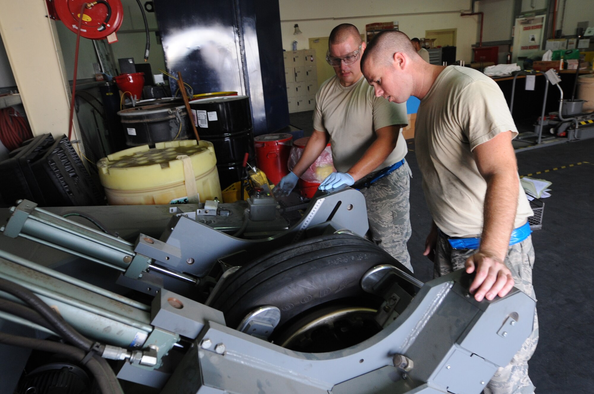 U.S. Air Force Tech. Sgt. Brandon Fitzpatrick, 380th Expeditionary Maintenance Squadron Crash Recovery shift lead, right, and U.S. Air Force Staff Sgt. Aaron Larson, 380th EMXS Crash Recovery craftsman, inspect a tire being compressed by a specialized machine at an undisclosed location in Southwest Asia Aug. 26, 2013. The machine allows crash recovery to remove an old tire so the wheel can be inspected. Fitzpatrick calls Huntington Beach, Calif., home, Larson calls Alpena, Mich., home and they are both deployed from Mountain Home Air Force Base, Idaho. (U.S. Air Force photo by Staff Sgt. Jacob Morgan)