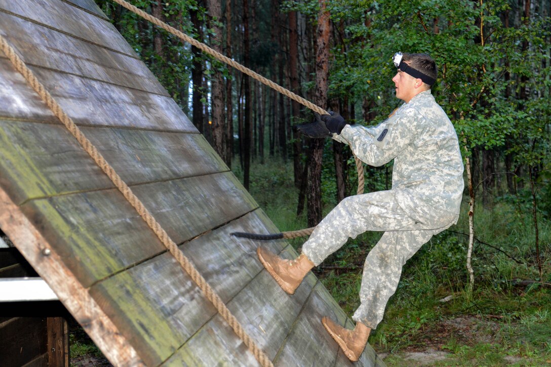 U.S. Army 2nd Lt. Michael Pikul climbs over the slanted wall on the obstacle course during U.S. Army Europe's Best Warrior competition in Grafenwoehr, Germany, Aug. 20, 2013. Pikul is assigned to the 30th Medical Command.