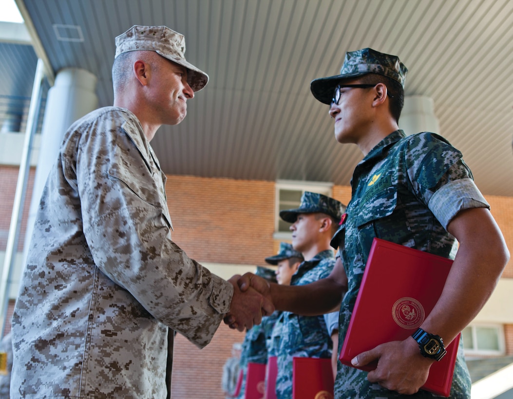 Lt. Col. Jason Brown shakes hands with Sgt. 1st Class Jin Su Bae Aug. 26 during an awards ceremony at a military location near the Rodriguez Live-Fire Complex. Bae received a U.S. Marine Corps certification of appreciation for his performance during Korean Marine Exchange Program 13-8, an annual exercise designed to enhance the capabilities of ROK-U.S. relationships. Brown is the commander of 3rd Battalion, 12th Marine Regiment, 3rd Marine Division, III Marine Expeditionary Force. Bae is an artilleryman with 5th Battalion, 2nd ROK Regiment, 2nd ROK Division.  