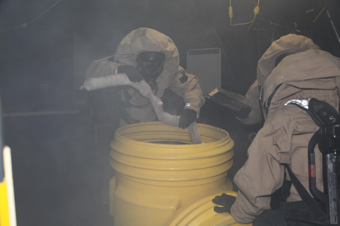 Marines secure a leaking barrel in a sealed container for transport during a unit training exercise Aug. 23 at a warehouse on Camp Kinser. A fog machine was used to simulate harmful gasses, barrels, gas tanks were provided as demonstrations of unsecured contaminants, and several false bodies were used to simulate casualties the teams were required to extract during the exercise. The teams consisted of Marines from various units with III Marine Expeditionary Force. 