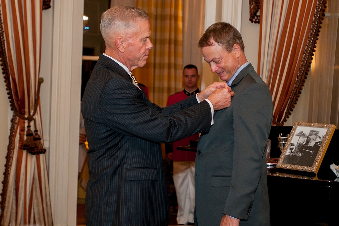 Gen. James F. Amos, commandant of the Marine Corps, pins an eagle, globe, and anchor emblem lapel pin on actor and musician, Gary A. Sinise, after naming him an honorary Marine at Marine Barracks Washington, D.C., Aug. 29.