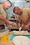 U.S. Army Sgt. Paul Marshall, an agricultural specialist with the Mississippi National Guard's Agricultural Development Team 4 and Plutonier Eugen Arsene with the Romanian 21st Mountain Battalion spread their mixture of bee food into gauze wrapping at Forward Operating Base Mescal, Afghanistan, Nov. 16, 2012.