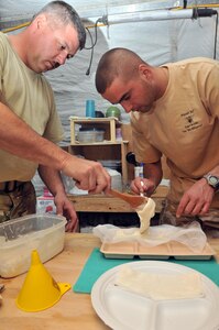 U.S. Army Sgt. Paul Marshall, an agricultural specialist with the Mississippi National Guard's Agricultural Development Team 4 and Plutonier Eugen Arsene with the Romanian 21st Mountain Battalion spread their mixture of bee food into gauze wrapping at Forward Operating Base Mescal, Afghanistan, Nov. 16, 2012.