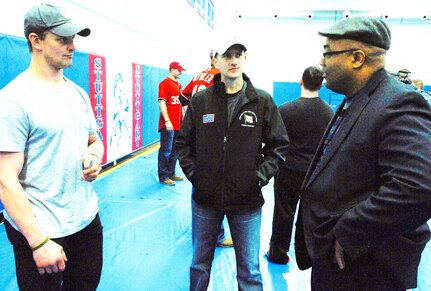 Shane Hudella, center, founder of the non-profit organization Defending the Blue Line, which donates hockey equipment to military families, chats with Matt Hendricks, left, a National Hockey League player with the Washington Capitals, and a local hockey fan before a United Service Organizations show at Patch Barracks in Stuttgart, Germany, Dec. 17, 2012.