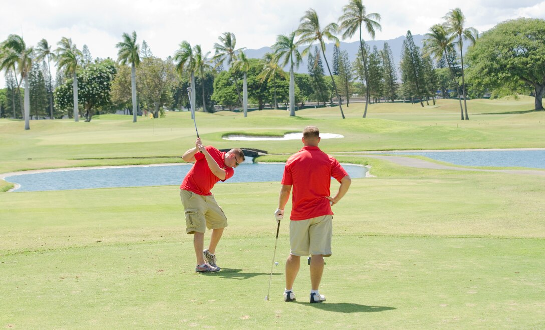 Staff Sgt. Matthew Steffen, section leader, Wounded Warrior Battalion West-Detachment Hawaii (left) takes a swing as Staff Sgt. Brian Koehn, operations chief for the detachment, watches during the 10th annual Navy League Golf Tournament at the Navy Marine Golf Course in Honolulu, Aug. 23, 2013. Members of the detachment, including spouses and friends volunteered for or participated in the tournament. (U.S. Marine Corps photo by Kristen Wong)