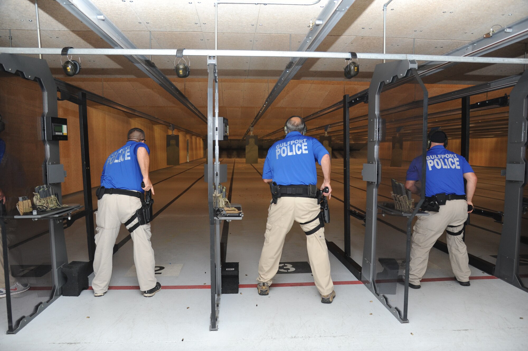Sergeants Jacob Smith, Paul Podlin and T.J. King, Gulfport Police Department, draw their weapons during the second annual Air Force Office of Special Investigations and the 81st Security Forces Squadron’s pistol shoot-off competition Aug. 30, 2013, at the indoor firing range, Keesler Air Force Base, Miss.  Gulfport placed first among the nine five-man teams from local law enforcement agencies that competed in the event.  (U.S. Air Force photo by Kemberly Groue)