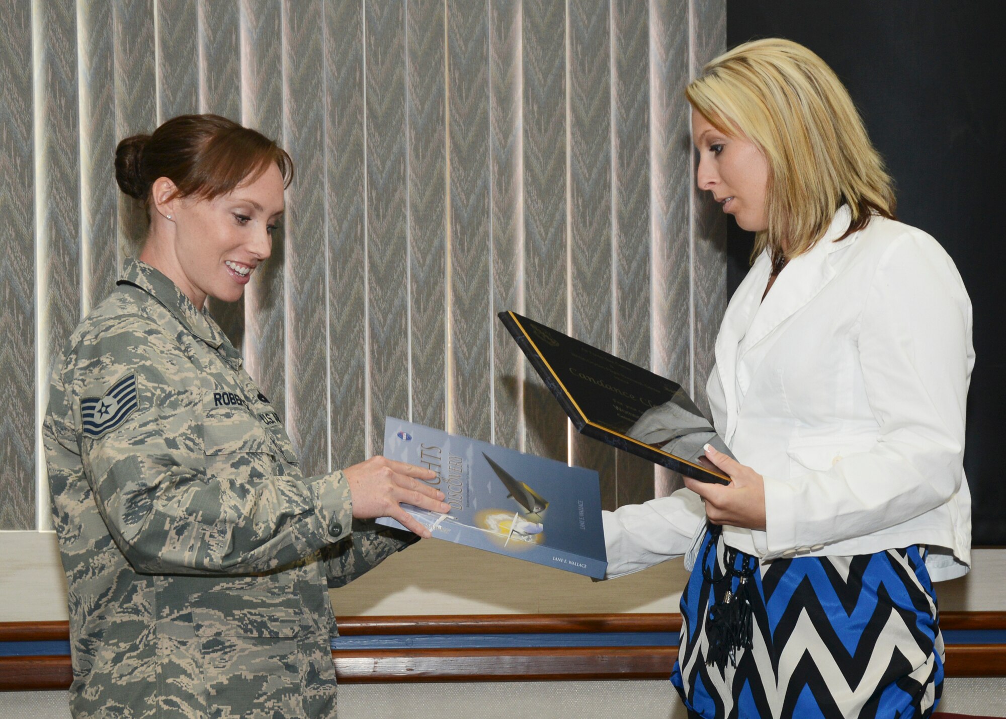 Tech. Sgt. Lissa Roberts, chairperson for the Women’s Equality Day Observance Planning Committee, presents Candance Clements with a plaque and a copy of NASA's “Flights of Discovery” for her presentation given at Edwards' Women's Equality Breakfast Aug. 27. (U.S. Air Force photo by Rebecca Amber)