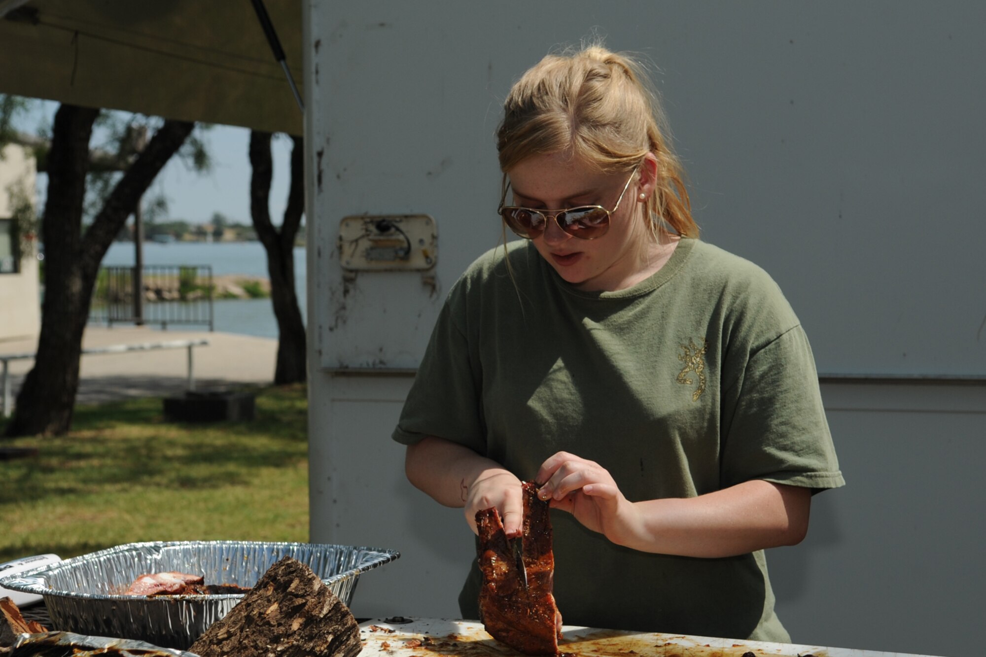 SAN ANGELO, Texas -- Airman 1st Class Kaitlin LeVasseur, 17th Training Wing Command Post, cuts ribs during a cooking class at the Goodfellow Recreation Camp Aug. 24. The 17th Force Support Squadron hosted a ribs cooking class where base members came out to learn how to cook ribs and jalapeno poppers on the grill. (U.S. Air Force photo/Staff Sgt. Laura R. McFarlane)