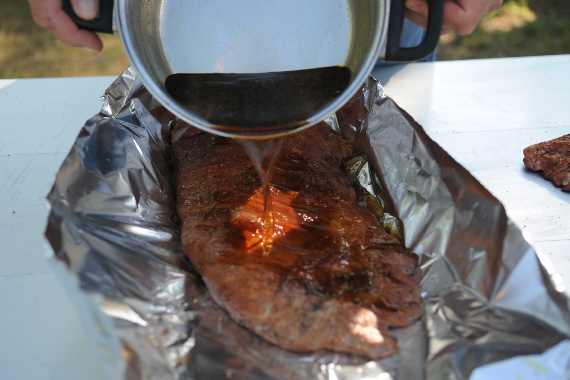 SAN ANGELO, Texas -- A grilling student pores a butter and brown sugar mixture onto ribs during a cooking class at the Goodfellow Recreation Camp Aug. 24. The student poured the mixture over the ribs after they had been on the grill for around 40 minutes to an hour. (U.S. Air Force photo/Staff Sgt. Laura R. McFarlane)