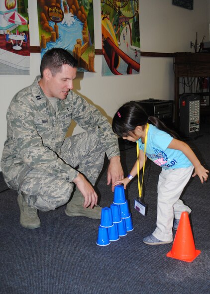 Ch. (Capt.) Rob Mohr, 341st Missile Wing chaplain, helps Levigh Quesada, 3, stack cups as part of a game Aug. 20.  Quesada was one of nearly 100 children who participated in this year’s Vacation Bible School.  (U.S. Air Force photo/Senior Airman Cortney Paxton)