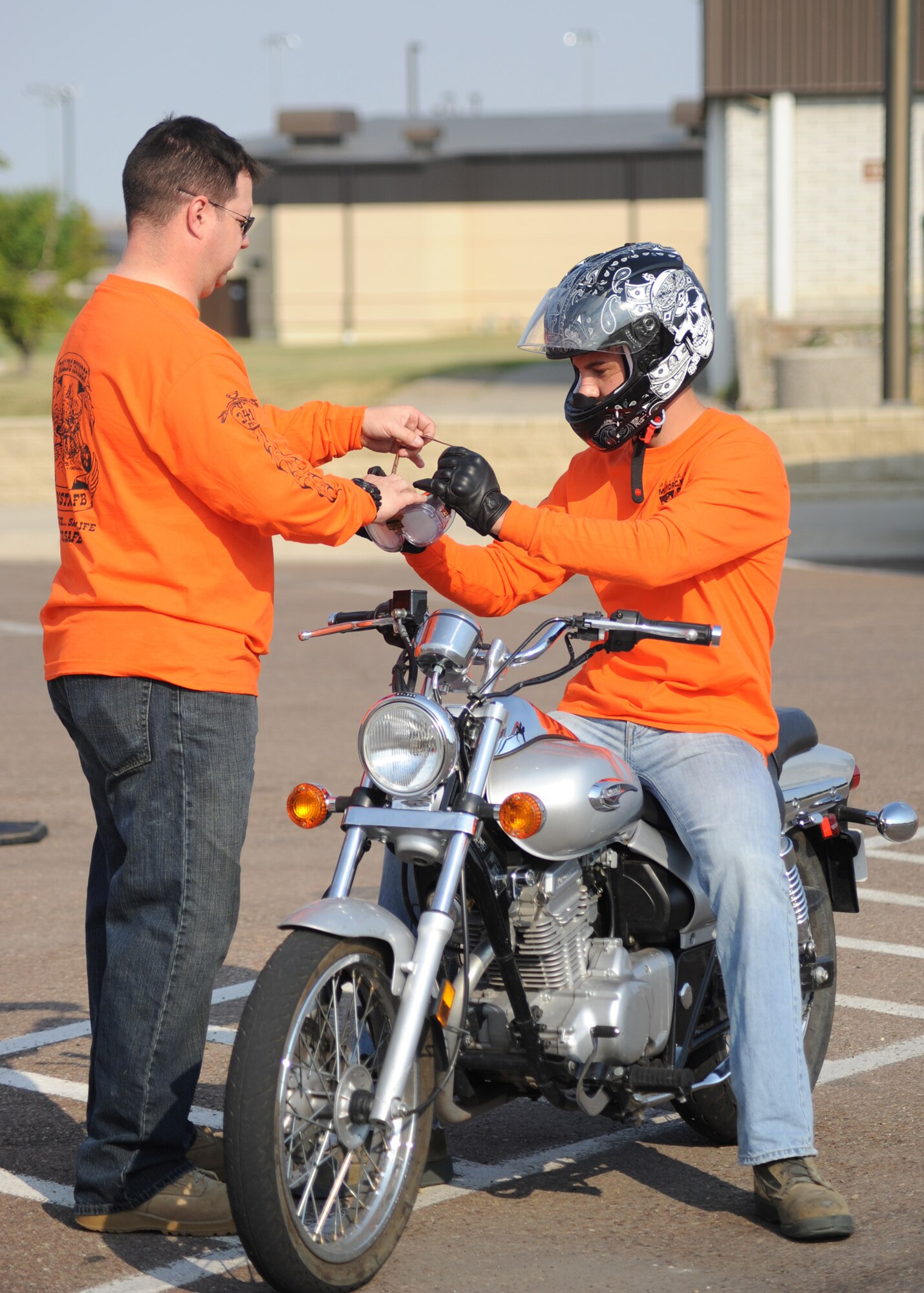 Master Sgt. Travis Pomeroy, 341st Civil Engineer Squadron unit security manager, helps Airman 1st Class Hudson Watson, 341st Maintenance Operations Squadron member, put on drunk driving goggles before doing a parking lot driving exercise at the Rolling Thunder motorcycle safety event Aug. 27.  Team Malmstrom members with motorcycle endorsements were able to see what it was like to drive a motorcycle with the goggles while trainers and safety personnel stood nearby.  (U.S. Air Force photo/Senior Airman Cortney Paxton)